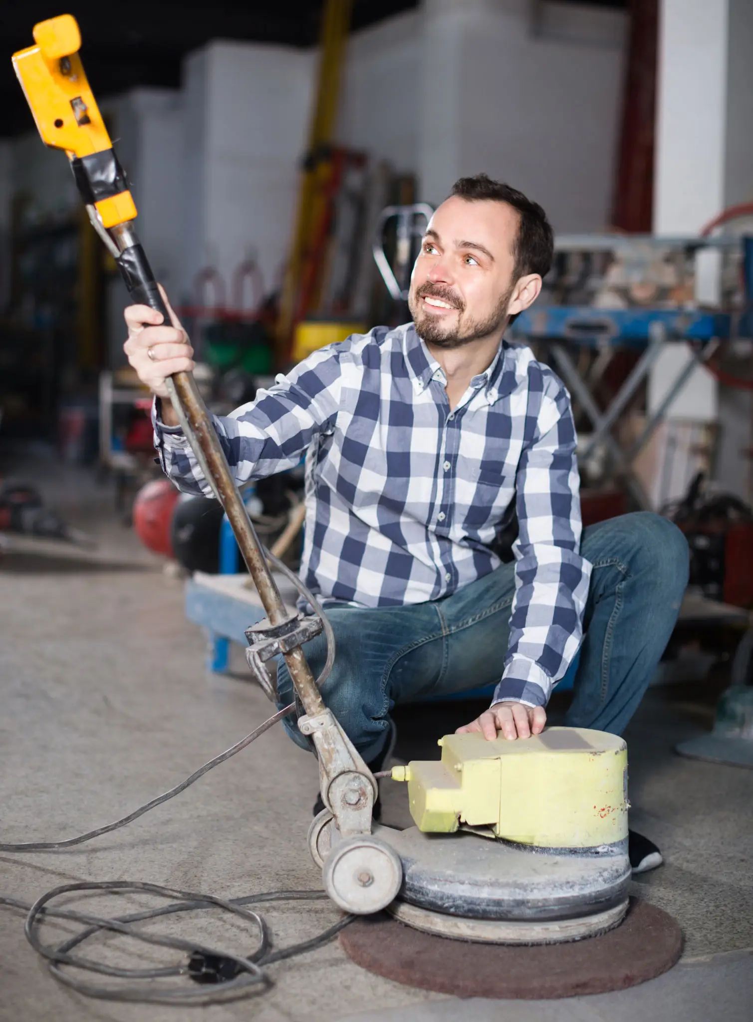 Young worker is using grinder for construction work at workshop.