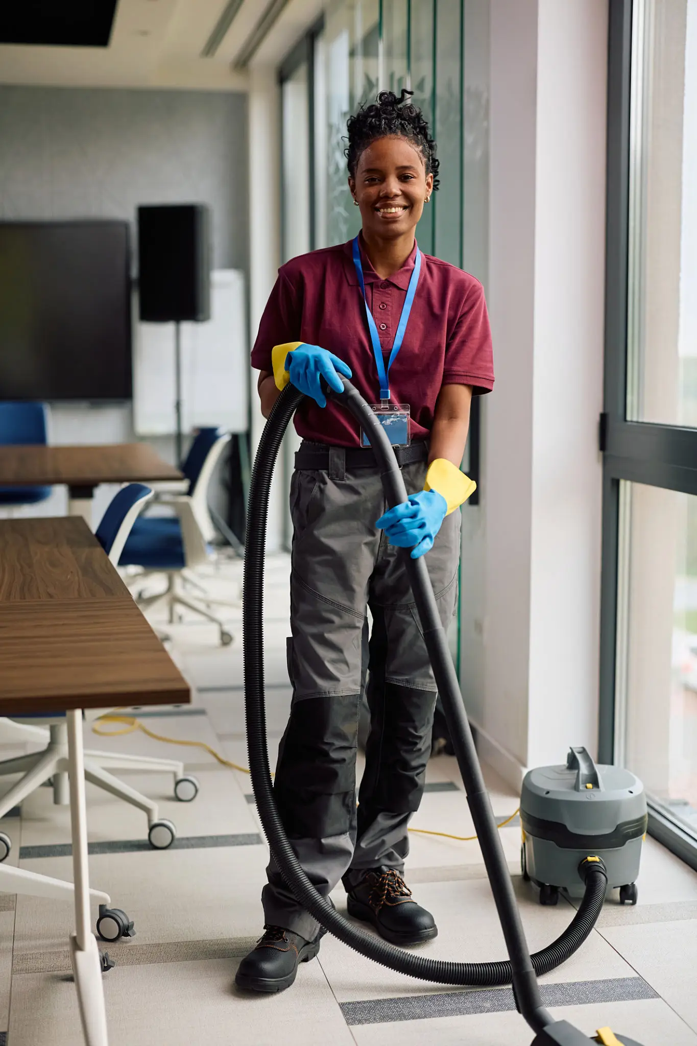African American female commercial cleaner maintaining the office building and looking at camera.