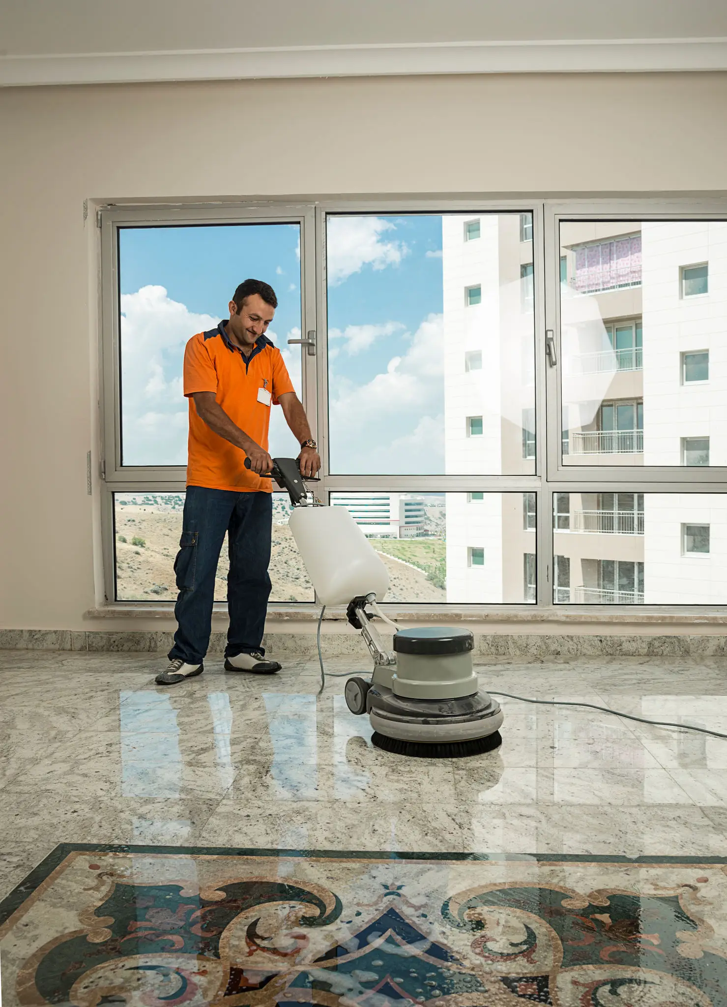 Manual worker cleaning the floor with buffer machine. 